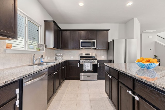 217 Timber Brook Dr, Hutto, TX 78634 - kitchen featuring appliances with stainless steel finishes, light stone counters, tasteful backsplash, dark brown cabinets, and recessed lighting