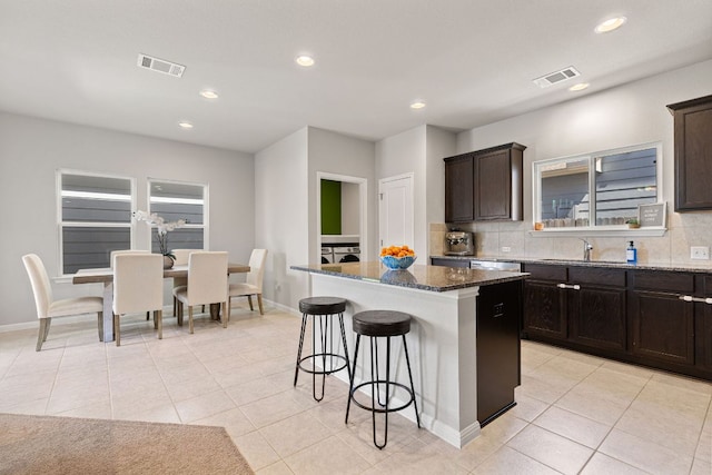 217 Timber Brook Dr, Hutto, TX 78634 - kitchen with a kitchen bar, dark stone countertops, a center island, decorative backsplash, and recessed lighting