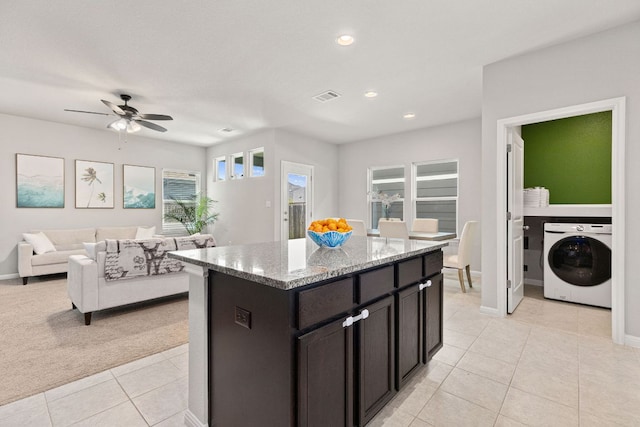 217 Timber Brook Dr, Hutto, TX 78634 - kitchen with washer / clothes dryer, light tile patterned floors, light stone counters, a center island, and recessed lighting