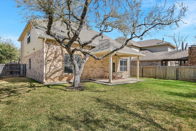 rear view of house with brick siding, a fenced backyard, a patio area, and a yard