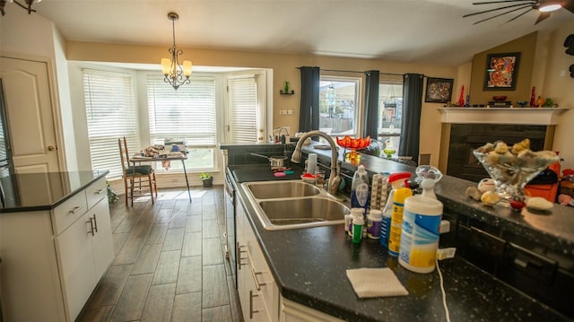 14811 Bescott Dr, Austin, TX 78728 - kitchen featuring dark countertops, wood finished floors, a sink, white cabinets, and a tile fireplace