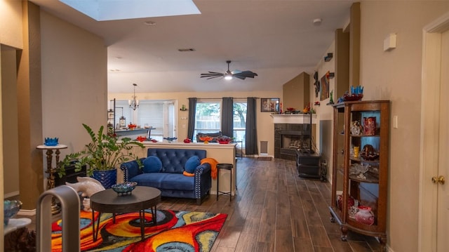 living area with baseboards, a tiled fireplace, visible vents, a skylight, and dark wood-style floors