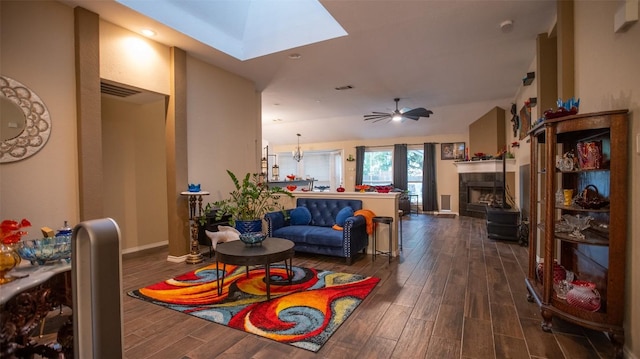 living room featuring a tiled fireplace, baseboards, dark wood-style floors, and visible vents