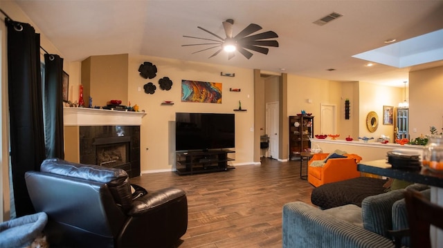 living room featuring wood finished floors, visible vents, recessed lighting, a fireplace, and lofted ceiling with skylight