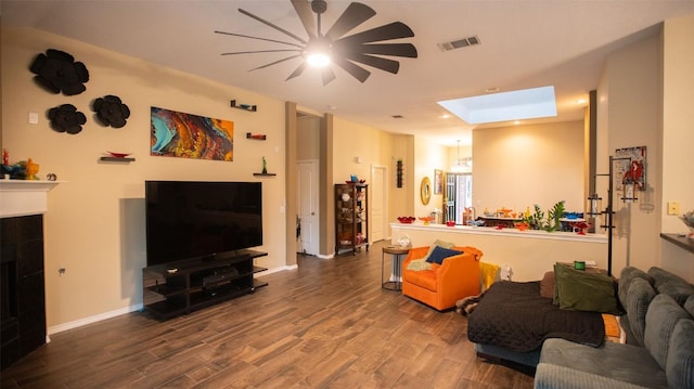 living area featuring a ceiling fan, visible vents, a skylight, and wood finished floors
