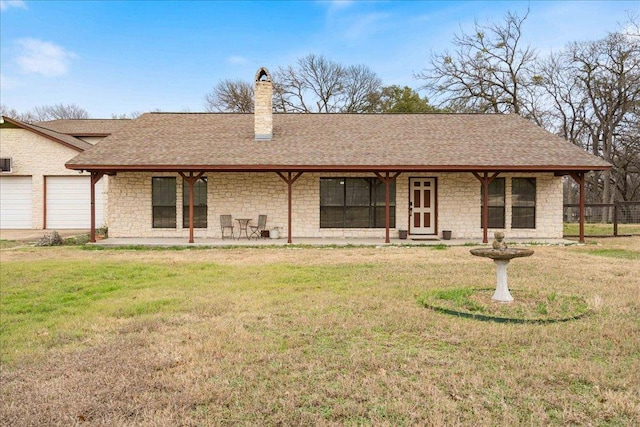 back of house featuring roof with shingles, a garage, a lawn, and a chimney