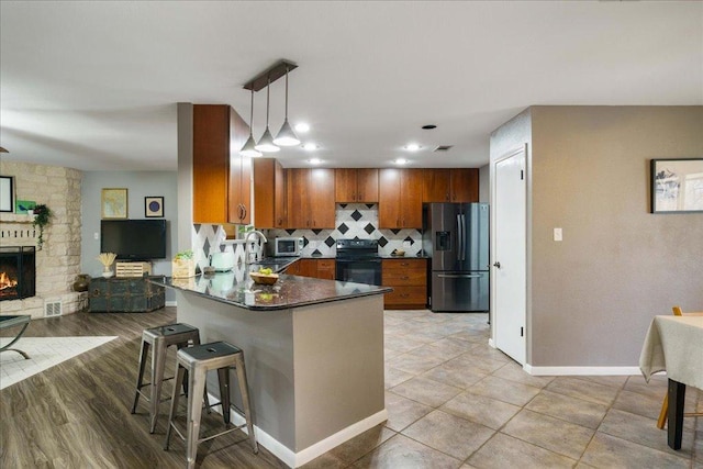 5014 Little Valley Rd, Leander, TX 78641 - kitchen with stainless steel appliances, a peninsula, brown cabinets, and decorative light fixtures