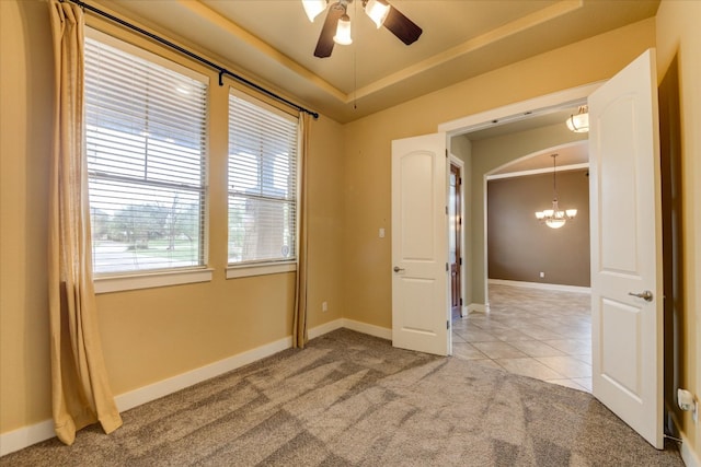10242 Brangus Rd, Driftwood, TX 78619 - empty room featuring light colored carpet, a chandelier, a ceiling fan, light tile patterned floors, and a tray ceiling