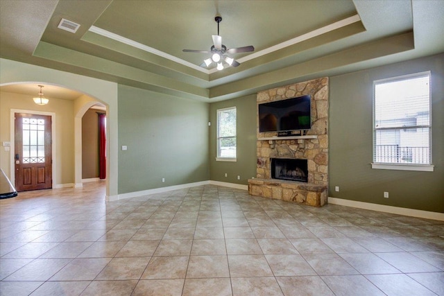 10242 Brangus Rd, Driftwood, TX 78619 - unfurnished living room with a raised ceiling, arched walkways, ceiling fan, a fireplace, and light tile patterned flooring