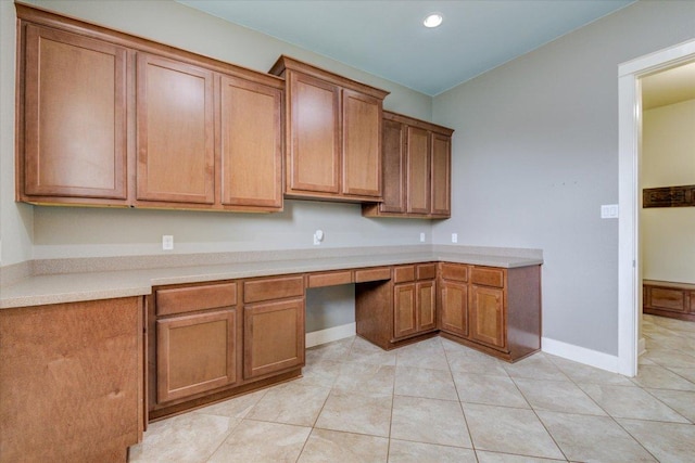 10242 Brangus Rd, Driftwood, TX 78619 - kitchen with brown cabinetry, light tile patterned flooring, built in study area, light countertops, and recessed lighting