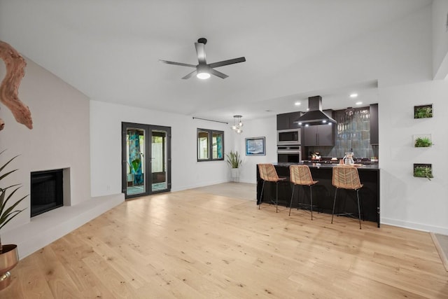 3503 Gable Dr, Austin, TX 78759 - kitchen featuring appliances with stainless steel finishes, island exhaust hood, a kitchen bar, light wood finished floors, and ceiling fan