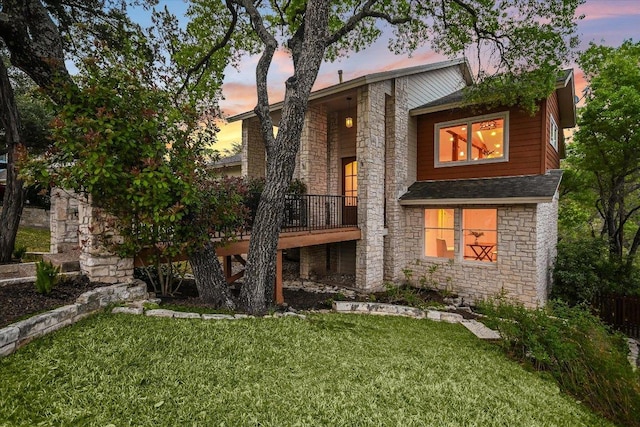 1607 Bay Hill Dr, Austin, TX 78746 - back of property at dusk with stone siding, a lawn, a wooden deck, and roof with shingles