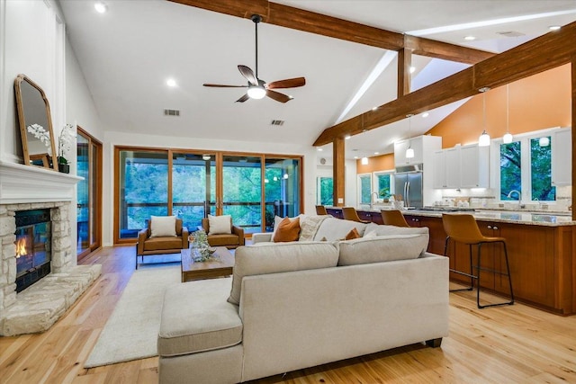 1607 Bay Hill Dr, Austin, TX 78746 - living area featuring high vaulted ceiling, beam ceiling, ceiling fan, light wood finished floors, and a stone fireplace