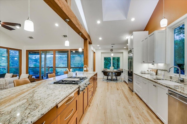 1607 Bay Hill Dr, Austin, TX 78746 - kitchen featuring appliances with stainless steel finishes, a sink, light wood-style flooring, light stone countertops, and hanging light fixtures