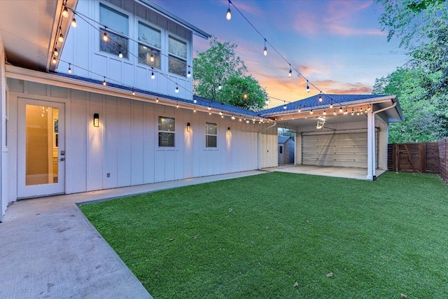 1811 Cedar Ave, Austin, TX 78702 - back of property at dusk with board and batten siding, a patio area, a detached garage, and an outbuilding