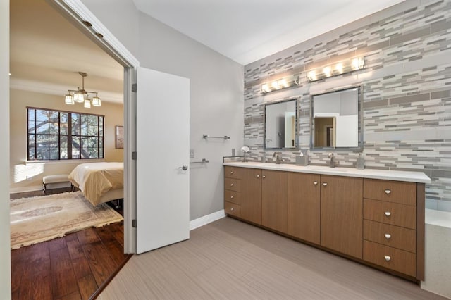 101 Knarr St, Austin, TX 78734 - bathroom featuring double vanity, a chandelier, connected bathroom, wood finished floors, and tasteful backsplash
