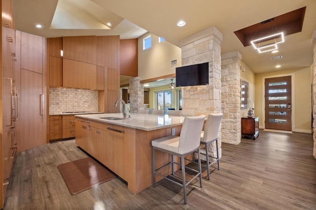 101 Knarr St, Austin, TX 78734 - kitchen featuring decorative columns, a kitchen bar, wood finished floors, decorative backsplash, and a large island with sink