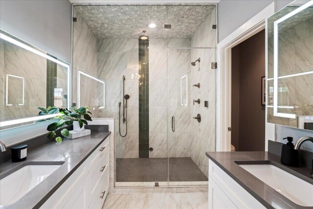 full bath with a stall shower, two vanities, and marble finish floors
