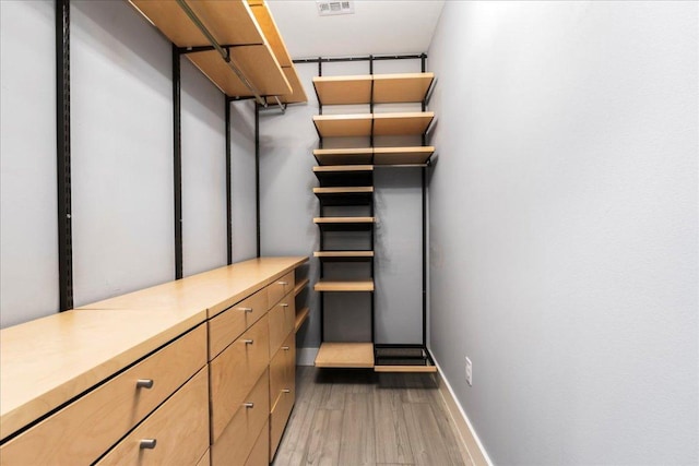 walk in closet with wood finished floors
