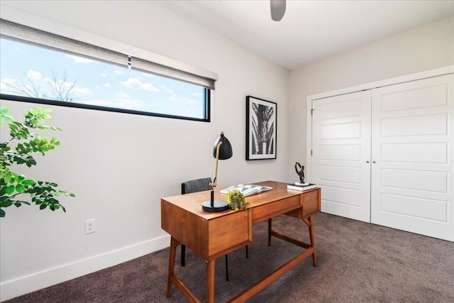 office featuring dark colored carpet, a ceiling fan, and baseboards
