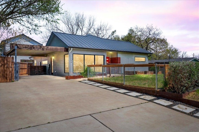 rear view of property with concrete driveway, a standing seam roof, and metal roof