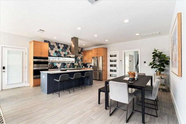 dining room with light wood-type flooring, recessed lighting, and baseboards