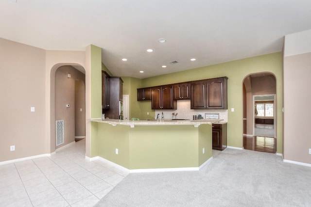 8016 Tahoe Parke Cir, Austin, TX 78726 - kitchen with arched walkways, light countertops, a peninsula, dark brown cabinets, and baseboards