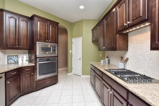 8016 Tahoe Parke Cir, Austin, TX 78726 - kitchen with appliances with stainless steel finishes, light tile patterned floors, tasteful backsplash, arched walkways, and dark brown cabinets