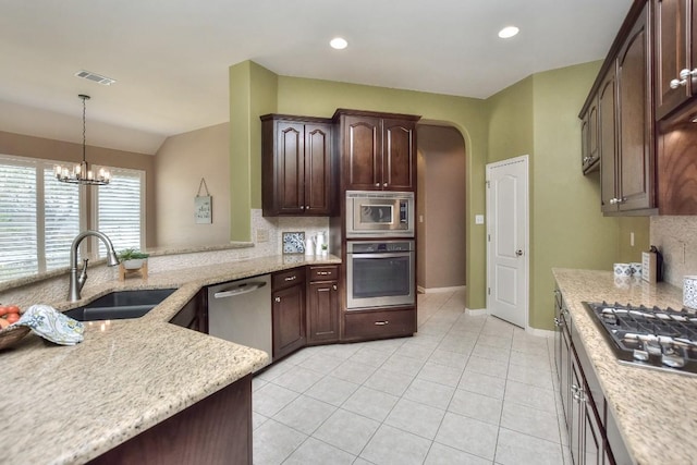 8016 Tahoe Parke Cir, Austin, TX 78726 - kitchen featuring appliances with stainless steel finishes, a sink, a chandelier, light stone counters, and lofted ceiling
