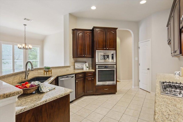 8016 Tahoe Parke Cir, Austin, TX 78726 - kitchen with stainless steel appliances, backsplash, light tile patterned floors, a chandelier, and light stone countertops