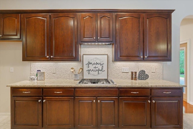 8016 Tahoe Parke Cir, Austin, TX 78726 - kitchen with stainless steel gas cooktop, light stone counters, tasteful backsplash, and arched walkways