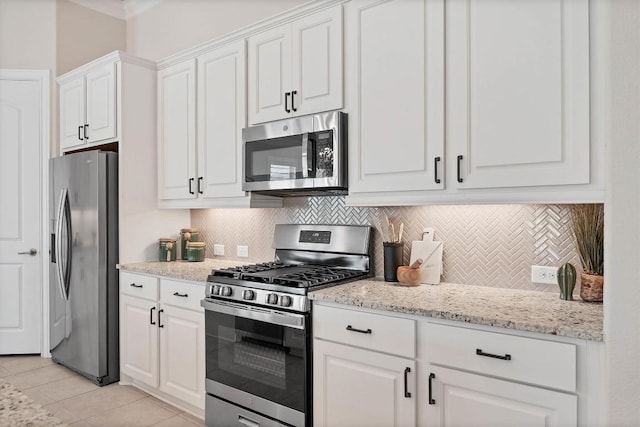 kitchen featuring tasteful backsplash, light stone countertops, white cabinetry, and appliances with stainless steel finishes
