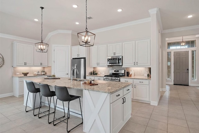 5141 Cornetto Blfs, Round Rock, TX 78665 - kitchen featuring appliances with stainless steel finishes, light tile patterned floors, ornamental molding, an island with sink, and tasteful backsplash