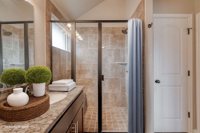 bathroom featuring a shower stall, vanity, and lofted ceiling