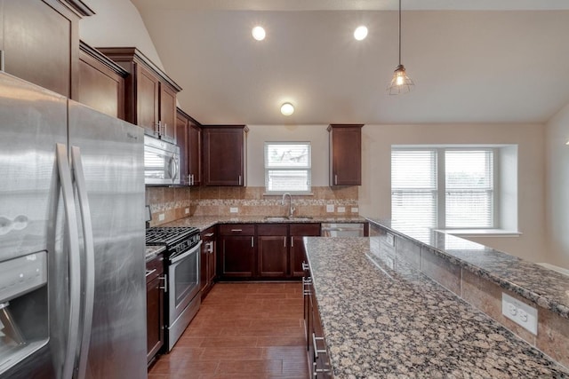 kitchen with stainless steel appliances, a sink, vaulted ceiling, decorative backsplash, and light stone countertops