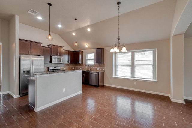 kitchen featuring appliances with stainless steel finishes, vaulted ceiling, tasteful backsplash, a chandelier, and dark brown cabinets