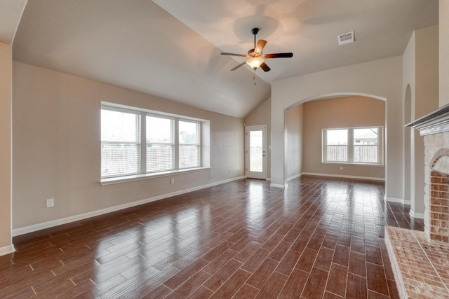 unfurnished living room featuring arched walkways, lofted ceiling, dark wood-type flooring, a ceiling fan, and baseboards