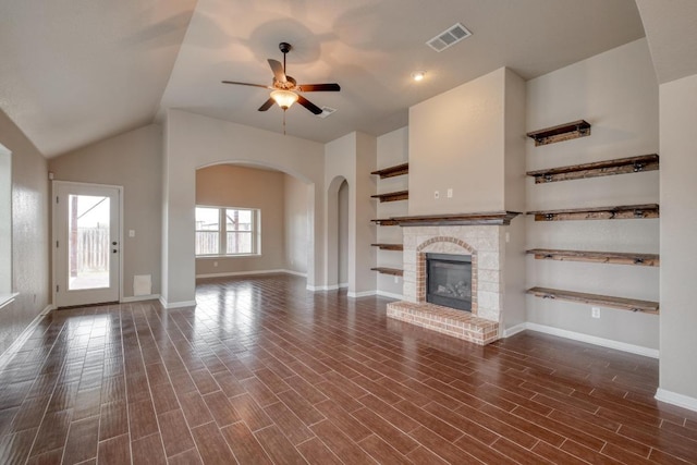 unfurnished living room featuring ceiling fan, a fireplace, baseboards, arched walkways, and dark wood-style flooring