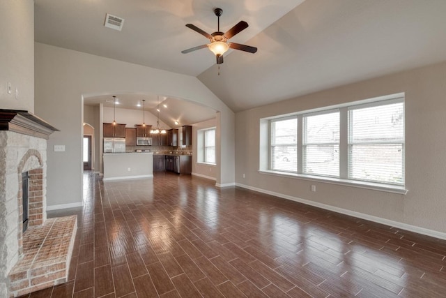 unfurnished living room with arched walkways, ceiling fan, vaulted ceiling, dark wood-type flooring, and baseboards