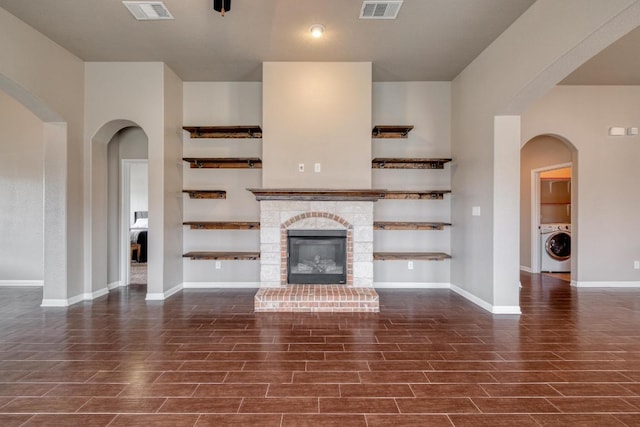 unfurnished living room with wood finish floors, baseboards, a fireplace, and washer / dryer