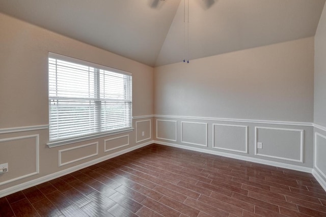 spare room featuring a wainscoted wall, a decorative wall, vaulted ceiling, and dark wood-style floors
