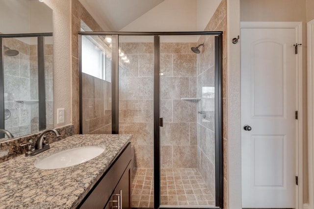 full bath with a stall shower, vanity, and lofted ceiling