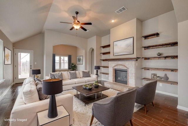 living area featuring arched walkways, dark wood-style flooring, baseboards, a fireplace, and ceiling fan