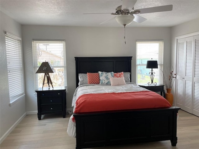 197 Port Saint Claire, Aransas Pass, TX 78336 - bedroom featuring light wood-style flooring, a textured ceiling, a closet, a ceiling fan, and baseboards