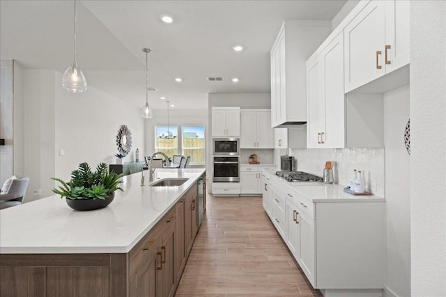 506 Diamondleaf Dr, Buda, TX 78610 - kitchen featuring stainless steel appliances, a sink, white cabinets, light wood-style flooring, and tasteful backsplash