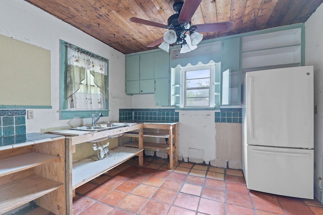 18309 Lake Oaks Dr, Jonestown, TX 78645 - kitchen featuring freestanding refrigerator, wood ceiling, tile counters, ceiling fan, and a sink