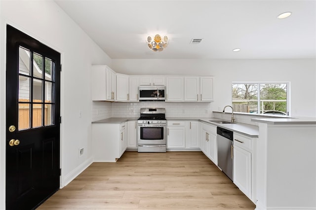 5408 Downs Dr Unit 1, Austin, TX 78721 - kitchen with appliances with stainless steel finishes, plenty of natural light, light wood-type flooring, tasteful backsplash, and recessed lighting