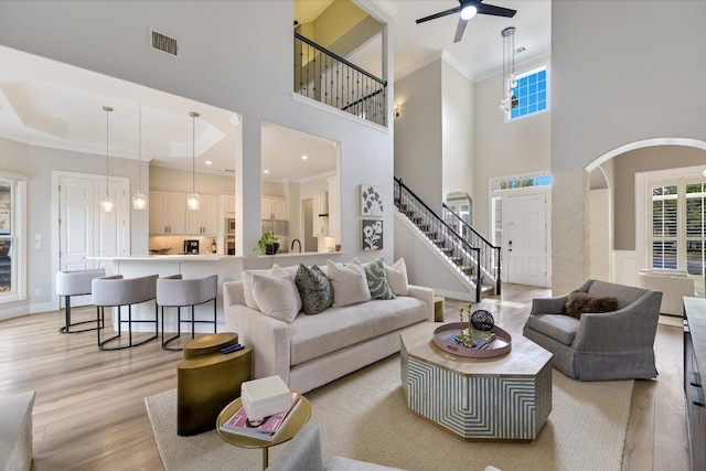 9204 Eddy Cv, Austin, TX 78735 - living room with light wood-style floors, a ceiling fan, stairway, arched walkways, and crown molding