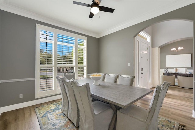 9204 Eddy Cv, Austin, TX 78735 - dining room featuring arched walkways, light wood finished floors, ceiling fan, a chandelier, and ornamental molding