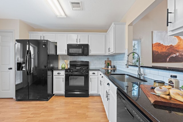 1142 Sundrop Pl, Round Rock, TX 78665 - kitchen featuring black appliances, white cabinetry, decorative backsplash, light wood-style flooring, and dark stone counters